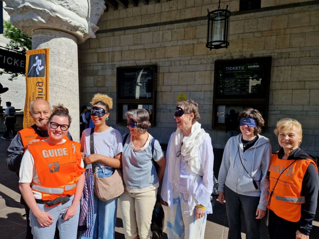 Einblick Basel: Guides Madeleine und Gabor und interessierte Passantinnen und Passanten mit Dunkelbrille