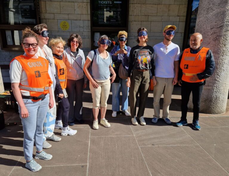 Einblick Basel: Guides Madeleine und Gabor und interessierte Passantinnen und Passanten mit Dunkelbrille