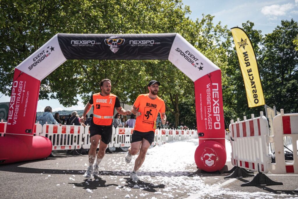 Justin mit Guide Kevin am Obstacle Run in Wettingen, im Zieleinlauf