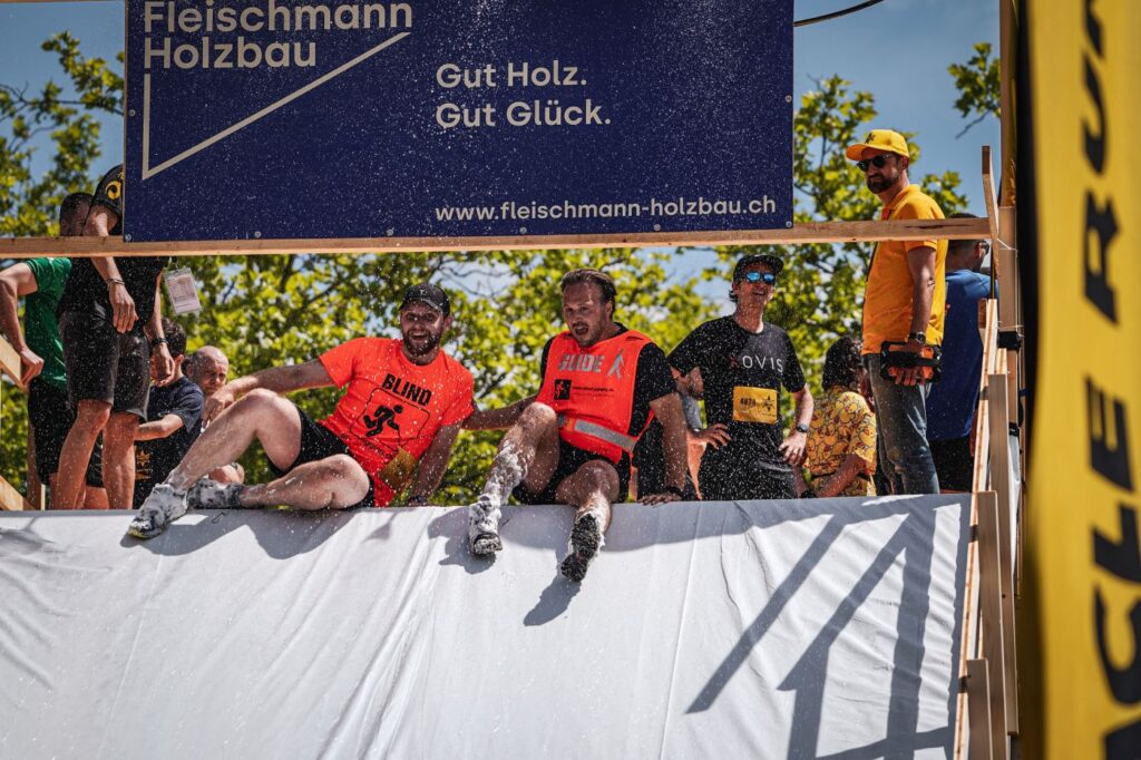 Justin mit Guide Kevin am Obstacle Run in Wettingen, am Herabrutschen nach einem Hindernis
