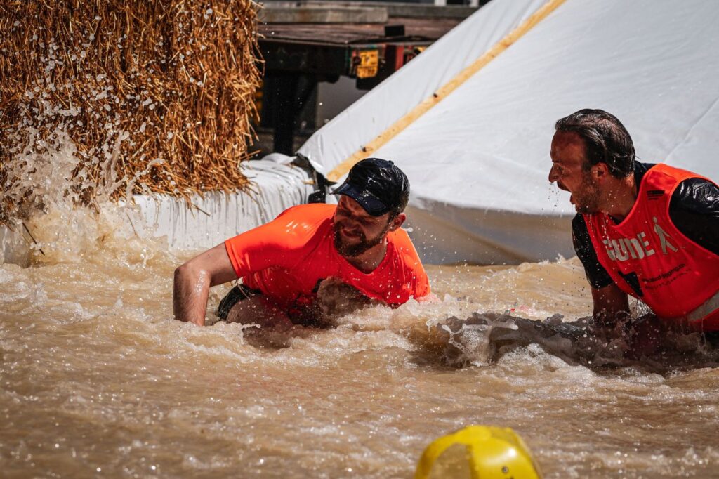 Justin mit Guide Kevin am Obstacle Run in Wettingen, am Überqueren des Schlammbades