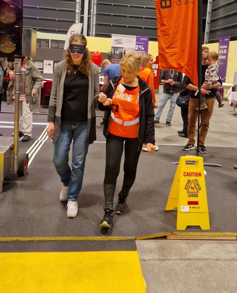 Guide Madeleine führt eine Teilnehmende durch den Parcours, an der Messe Neuland 2024