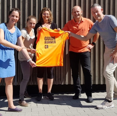 Blindenguides die nach der Guidesitzung "Guide-Runner" in St. Galen zusammen ein oranges T-Shirt halten